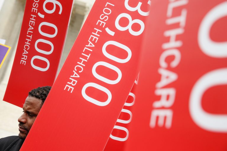 Ayru Crymef of Washington, and others with the Service Employees International Union, hold signs depicting numbers of people who have lost heath care coverage during a rally outside the Supreme Court in Washington, Wednesday, March 4, 2015, as the court was hearing arguments in King v. Burwell, a major test of President Barack Obama's health overhaul which, if successful, could halt health care premium subsidies in all the states where the federal government runs the insurance marketplaces. (AP Photo/Andrew Harnik)
