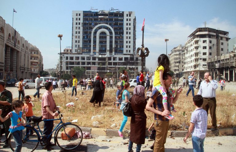 Syrian civilians fill a city square as they return to Homs, Syria on Friday, May 9, 2014. Bulldozers cleared rubble Friday from the streets of battle-scarred districts in the central Syrian city after government troops entered the last rebel-held neighborhoods as part of an agreement that also granted opposition fighters safe exit from the city. (AP Photo)