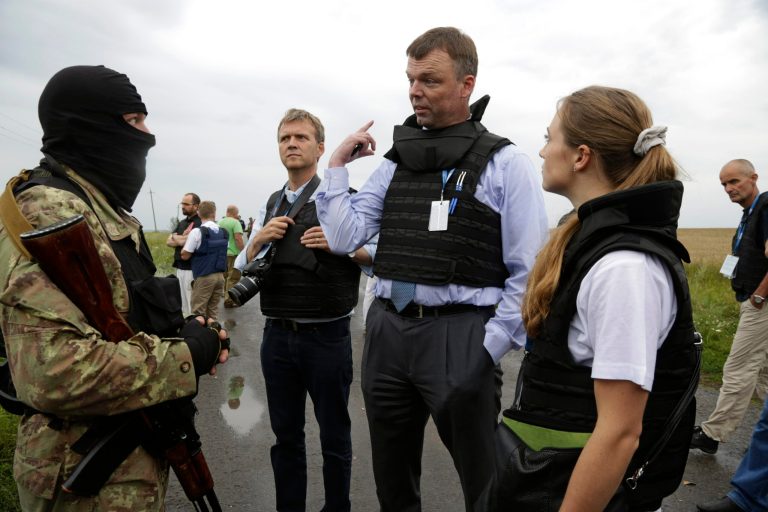 Representatives from the Organization for Security and Cooperation speak to a pro-Russia fighter at the crash site of a Malaysia Airlines jet near the village of Hrabove, Friday, July 18, 2014. Representatives from the Organization for Security and Cooperation in Europe and four Ukrainian experts had traveled into rebel-controlled areas to begin an investigation into the attack that killed 298 people from nearly a dozen nations. (AP Photo/Dmitry Lovetsky)