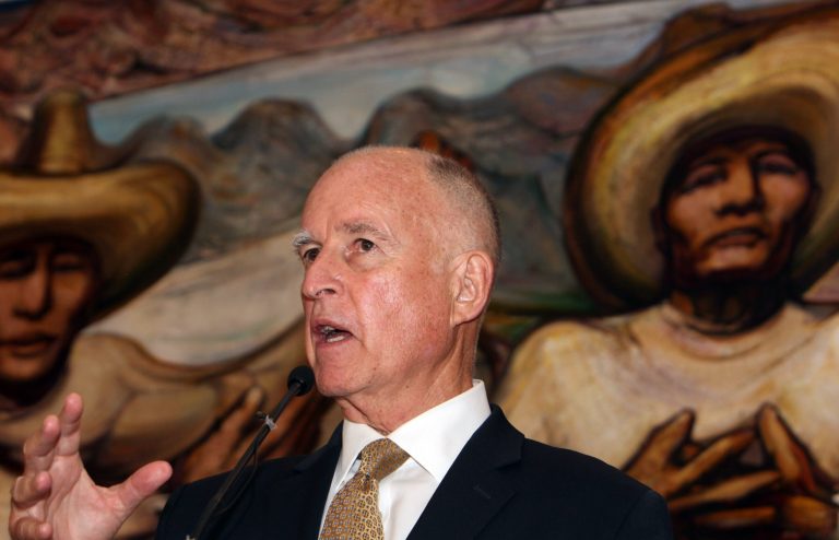 Back-dropped by a mural by Mexican painter David Alfaro Siqueiros, California Governor Jerry Brown speaks during a press conference with U.S. Ambassador to Mexico Anthony Wayne, not seen,  at the Soumaya museum in Mexico City, Monday, July 28, 2014.  California's governor on Monday kicked off a three day visit to Mexico, where he will discuss immigration in separate meetings with President Enrique Pena Nieto and Central American diplomatic and religious leaders.(AP Photo/Marco Ugarte)