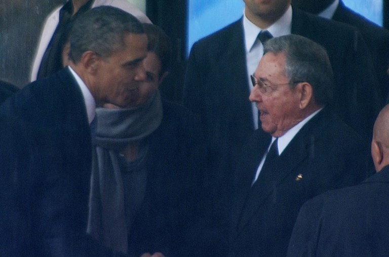 In this image from TV, US President Barack Obama shakes hands with Cuban President Raul Castro at the FNB Stadium in Soweto, South Africa, in the rain for a memorial service for former South African President Nelson Mandela, Tuesday Dec. 10, 2013. (AP Photo/SABC Pool)