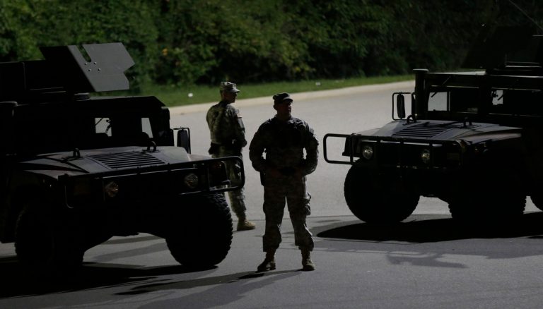 Members of the Missouri National Guard stand watch outside a command post near a protest Monday, for Michael Brown, who was killed by a police officer Aug. 9 in Ferguson, Mo. (AP Photo/Charlie Riedel)