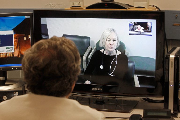   In this Thursday, Dec. 20, 2012 photo, Dr. Terry Rabinowitz, back to camera, talks with nurse Leslie Orelup at Helen Porter Nursing Home on in Burlington, Vt. New health insurance regulations in Vermont are giving a boost to telemedicine, the system that enables health care providers to offer consult with patients without being in the same room. Telemedicine isnât new, but the new regulations make it easier for physicians to be reimbursed for services performed by two-way video hookups. Fletcher Allen Telemedicine director Dr. Terry Rabinowitz says popular specialties are psychiatry and dermatology. (AP Photo/Toby Talbot)  