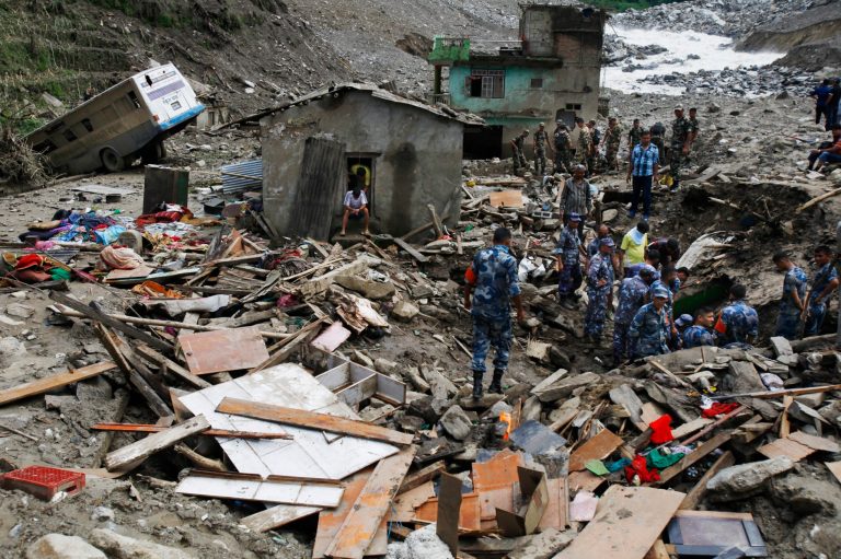 Nepalese rescuers search for bodies of victims of Saturday's landslide as a damaged school bus lies on left, in Mankha, about 120 kilometers (75 miles) east of Katmandu, Nepal, Monday, Aug.4, 2014. Nepalese authorities said there is no hope that more than 150 missing people are still alive after being buried by piles of rocks, mud and upturned trees.  (AP Photo/Niranjan Shrestha)
