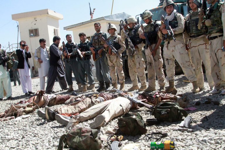 Afghan security forces stand guard near the dead bodies of Taliban fighters in Ghazni, Afghanistan, Thursday, Sept. 4, 2014. The Taliban struck a government compound in eastern Afghanistan early on Thursday in an attack that included two suicide truck bombings and left at least 12 people dead, including several off duty policemen asleep in their quarters nearby, officials said. (AP Photo/Rahmatullah Nikzad)