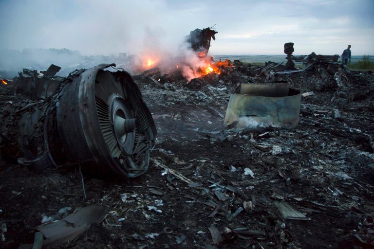 A man walks amongst the debris at the crash site of a passenger plane near the village of Grabovo, Ukraine, Thursday, July 17, 2014. Ukraine said a passenger plane carrying 295 people was shot down Thursday as it flew over the country, and both the government and the pro-Russia separatists fighting in the region denied any responsibility for downing the plane. (AP Photo/Dmitry Lovetsky)