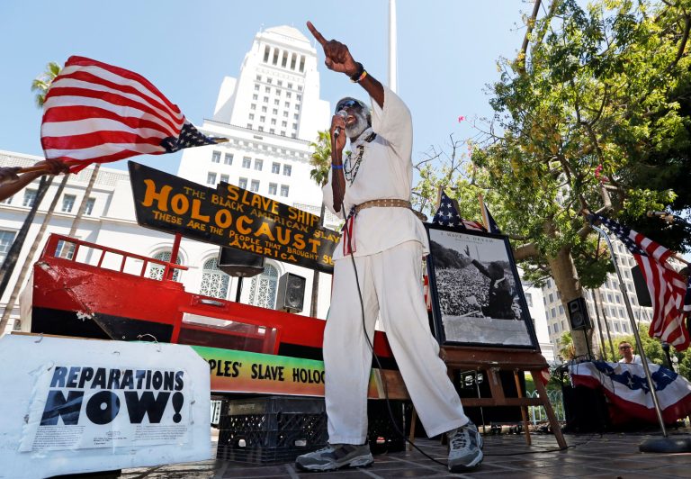 Los Angeles activist Ted Hayes stands with a scale model of a slave ship, in which thousands of slaves were brought to North America, during a rally to commemorate the 50th anniversary of the March On Washington, at Los Angeles City Hall Wednesday, Aug. 28, 2013. (AP Photo/Reed Saxon)