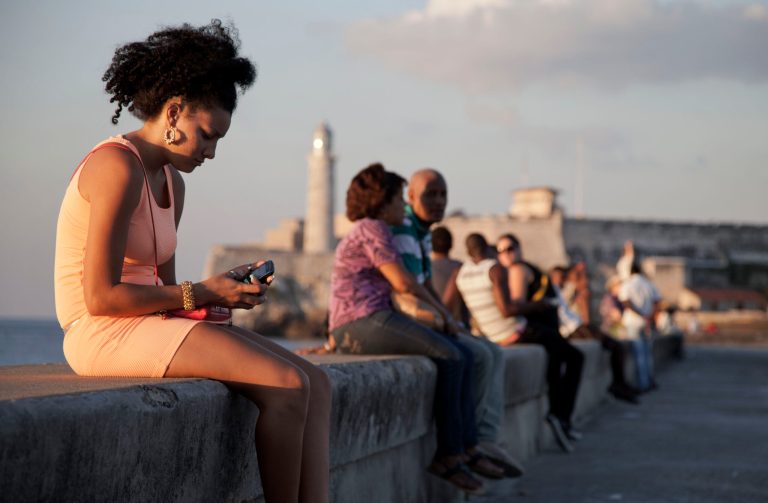 In this March 11, 2014 photo, a woman uses her cellphone as she sits on the Malecon in Havana, Cuba. (AP Photo/Franklin Reyes)