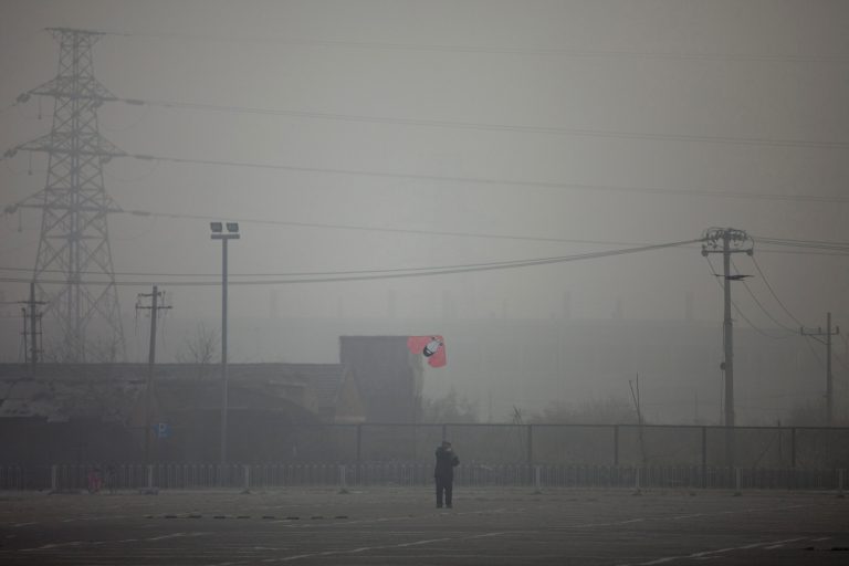 FILE - In this Jan. 12, 2013 photo, a man flies a kite near electricity pylons on a hazy day in Beijing. While the numbers are hard to quantify, executive recruitment consultants say they are noticing that it is becoming harder to attract top talent to China - both expats and Chinese nationals educated abroad. If the polluted skies continue, companies may have to fork out more money for their workers, settle for less qualified candidates or hire local workers instead of expats. (AP Photo/Alexander F. Yuan, File)