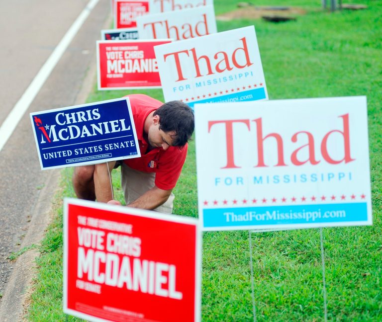 A man straightens a Chris McDaniel signs outside the voting booths at the Oxford Conference Center in Oxford, Miss., on Tuesday. (AP Photo/Oxford Eagle, Bruce Newman)