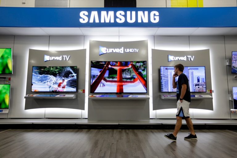 In this Wednesday, June 18, 2014 photo, a customer walks past a display featuring a Samsung 78-inch curved television on display at a Best Buy store in Greenwood, Ind. The 78-inch television is flanked by 65-inch versions. Americans increasingly are replacing their once-enviable 50-inch TVs with even bigger screens. (AP Photo/Michael Conroy)