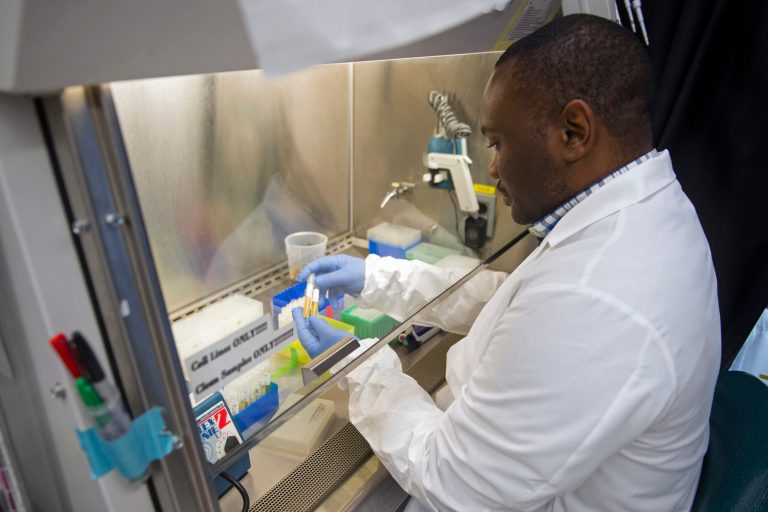 In this photo taken Feb. 4, 2015, biologist Olivier Mbaya works with serum samples from healthy volunteer participants in a European study of an experimental Ebola vaccine, at the Vaccine Research Center at the National Institutes of Health in Bethesda, Md. (AP Photo/Cliff Owen)