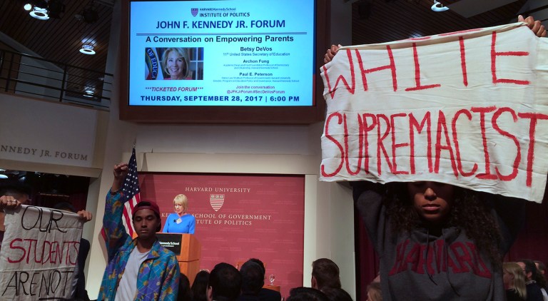 Protesters stand and hold signs and demonstrate during a speech by Education Secretary Betsy DeVos at Harvard University's Kennedy School of Government in Cambridge. (AP Photo/Maria Danilova)