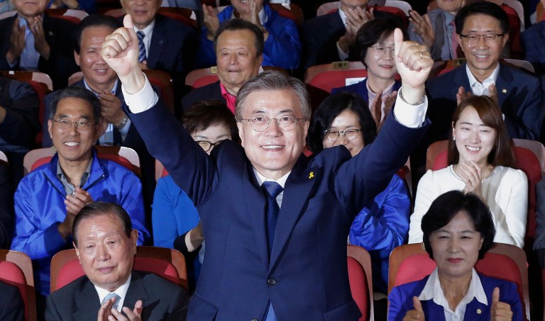 South Korea's presidential candidate Moon Jae-in of the Democratic Party raises his hands as his party leaders and members watch on television local media's results of exit polls for the presidential election in Seoul, South Korea, Tuesday, May 9, 2017. (AP Photo/Ahn Young-joon)