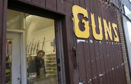 Rifles line a wall above in front of people standing in a gun shop Wednesday, Dec. 19, 2012, in Seattle. The reaction to the Connecticut school shooting can be seen in gun stores and self-defense retailers across the nation: Anxious parents are fueling sales of armored backpacks for children while firearms enthusiasts are stocking up on assault rifles in anticipation of tighter gun control measures. (AP Photo/Elaine Thompson)