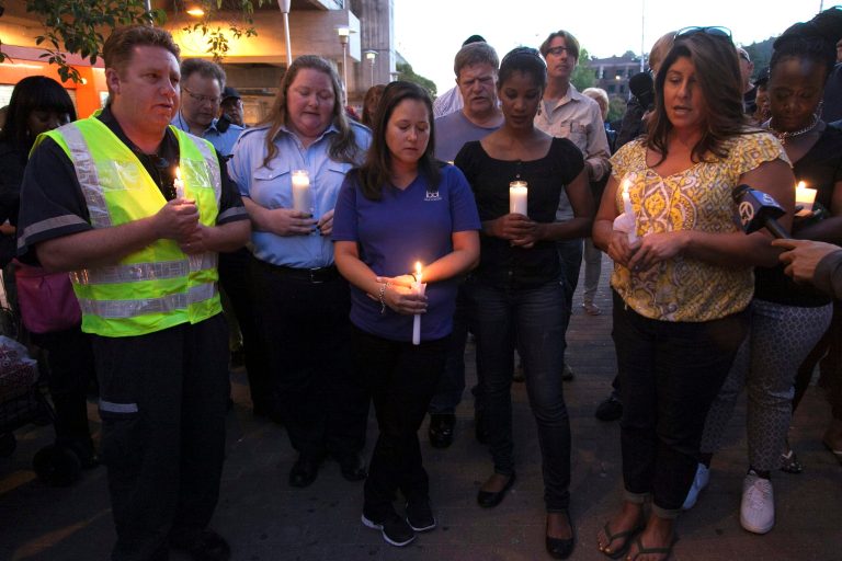Mourners hold candles to honor the memory of two workers who were killed during a train accident in Walnut Creek, Calif., Sunday, Oct. 20, 2013. Two federal accident investigators arrived in the San Francisco Bay area on Sunday to examine the deaths of two transit workers who on Saturday, were struck by an out-of-service commuter train performing routine maintenance against the backdrop of a labor strike. (AP Photo/Eric Slomanson)