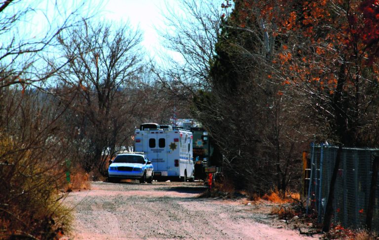 Bernalillo County authorities are stationed outside a home south of Albuquerque, N.M., on Sunday, Jan. 20, 2013, where two adults and three children were found shot to death. Authorities say a teenager has been arrested and booked on murder and other charges in connection with the shootings. (AP Photo/Susan Montoya Bryan)