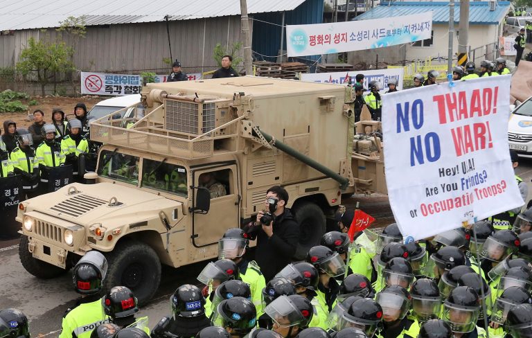 A U.S. military vehicle moves past banners opposing a plan to deploy an advanced U.S. missile defense system called Terminal High Altitude Area Defense, or THAAD, as South Korean police officers stand guard in Seongju, South Korea, Wednesday. (Kim Jun-hum/Yonhap via AP)