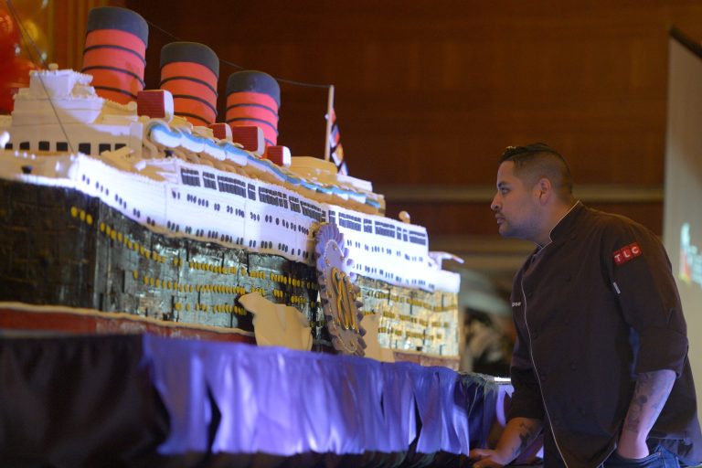 Baker Jose Barajas looks over his 15-foot long, 600-pound cake built to replicate the Queen Mary to celebrate its 80th anniversary of her launching in Long Beach, Calif.,  on Friday, Sept. 26, 2014. After some speeches and a short film, guests were able to sample a slice of the cake.  (AP Photo/The Daily Breeze,  Scott Varley)