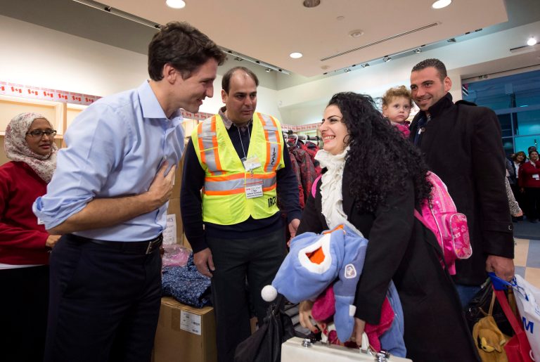 Prime Minister Justin Trudeau, left, greets refugees fleeing from Syria, as they arrive at Pearson International airport, in Toronto. (Nathan Denette/The Canadian Press via AP)
