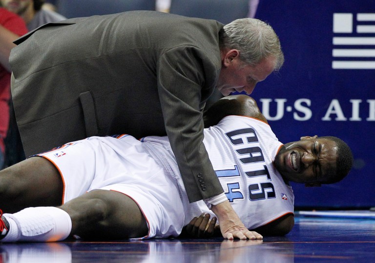   A trainer checks on injured Charlotte Bobcats' Michael Kidd-Gilchrist (14) during the first half of an NBA basketball game against the San Antonio Spurs in Charlotte, N.C., Saturday, Dec. 8, 2012. (AP Photo/Chuck Burton)  