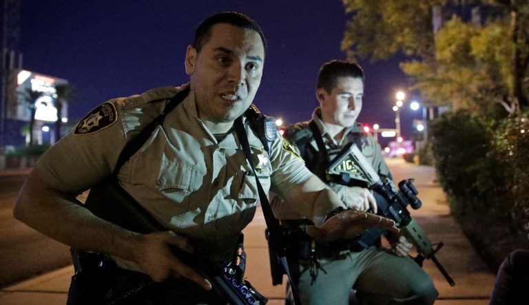 Police officers advise people to take cover near the scene of a shooting near the Mandalay Bay resort on the Las Vegas Strip. The Las Vegas police said that suspected shooter Stephen Paddock appears to have committed suicide before federal agents broke into his hotel room. (AP Photo/John Locher)