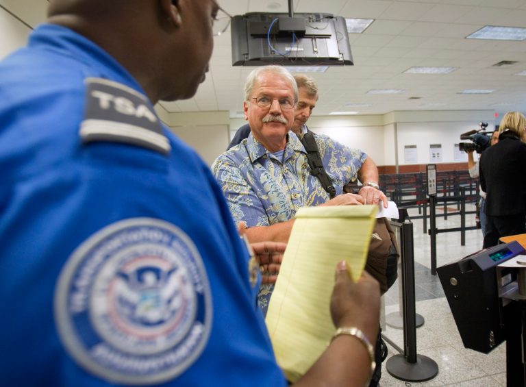 FILE - In this Oct. 4, 2011 file photo, passenger Don Heim, right, of Alpharetta, Ga., is briefed by Transportation Security Administration trainer Byron Gibson before going through a new expedited security line at Hartsfield-Jackson International Airport in Atlanta.  The news that a man flew from Liberia to the U.S. after exposure to Ebola, and wound up in a hospital isolation ward, has led to calls for tougher measures to protect Americans, such as a ban on flights from countries hit by the epidemic. Federal health officials and airlines have dismissed any risk to passengers who flew with the man last month and say they are protecting travelers by screening passengers and wiping down airplane cabins nightly.  (AP Photo/David Goldman)