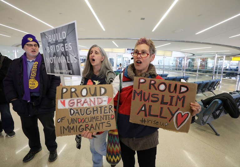 Kevin Brown of the Service Employees International Union, Kelly McDonald, of Montclair, and Jessica Sporn, of Montclair, chant in protest of the travel ban before the start of a press conference, Thursday, at Newark Airport, in Newark, N.J. (Chris Pedota/The Record via AP)