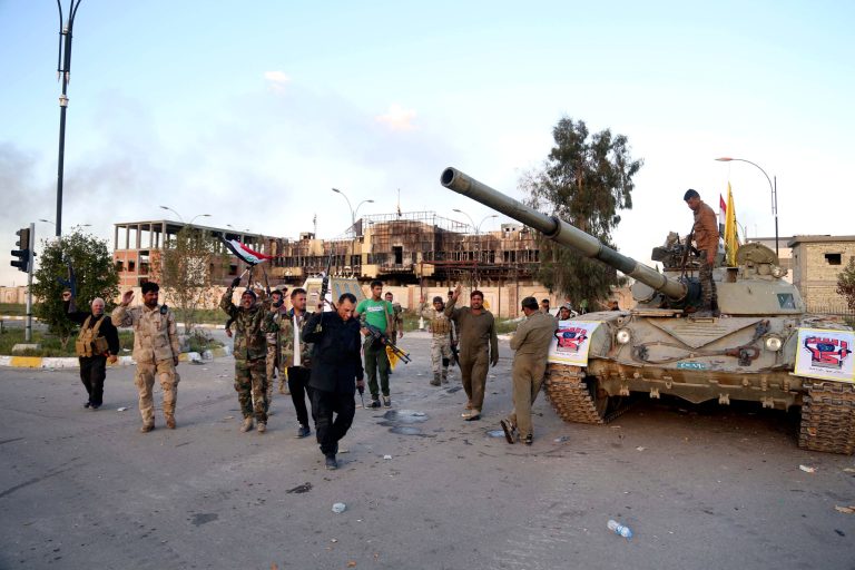 Iraqi security forces and allied Shiite militiamen celebrate in front of the provincial council building in Tikrit, 80 miles (130 kilometers) north of Baghdad, Iraq, Tuesday, March 31, 2015. Iraqi forces battled Islamic State militants holed up in downtown Tikrit, going house to house Tuesday in search of snipers and booby traps, and the prime minister announced security forces had reached the city's center. (AP Photo/Khalid Mohammed)