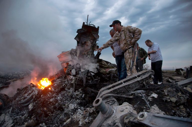 FILE - In this Thursday, July 17, 2014 file photo, people inspect the crash site of a passenger plane near the village of Grabovo, Ukraine. All 298 people aboard the Malaysia Airlines Flight 17 traveling from Amsterdam to Kuala Lumpur were killed. (AP Photo/Dmitry Lovetsky)
