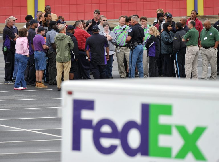 A Cobb County Police Officer speaks to FedEx employees and family members gathered at the parking lot of a skating rink located near the shipping facility where a gunman open fire in Kennesaw, Ga., on Tuesday, April 29, 2014.  A shooter described as being armed with an assault rifle and having bullets strapped across his chest 