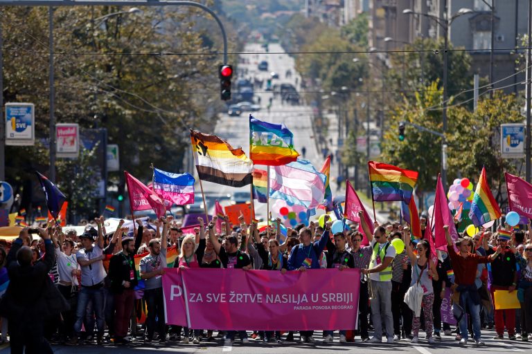 Gay activists wave flags during the Pride March in Belgrade, Serbia, Sunday, Sept. 28, 2014. Waving hundreds of rainbow-colored flags, several hundred gay activists marched from the government headquarters through the empty Belgrade streets where shops were closed and public transport was stopped. Sign reads 