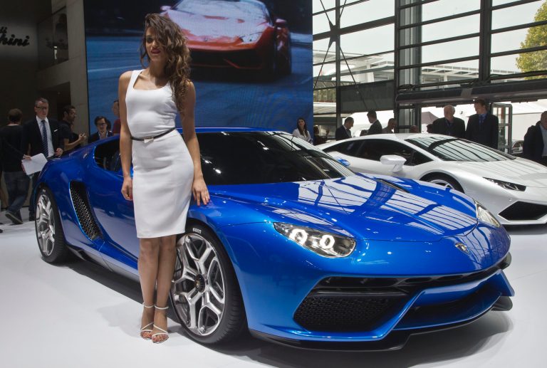 A hostess poses next to a Lamborghini Asterion LPI 910-4 AT during the press day at the Motor Show in Paris, France, Thursday, Oct. 2, 2014. European carmakers are hoping to impress with new models at this week's Paris Motor Show and prove they have come out stronger from years of economic trouble and cost-cutting. (AP Photo/Michel Euler)
