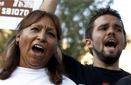 Maria Cruz, left, and Lincoln Statler chant as they join dozens who rally in front of U.S. Immigration and Customs Enforcement building in Phoenix, protesting Arizona's immigration law. (AP Photo/Ross D. Franklin)