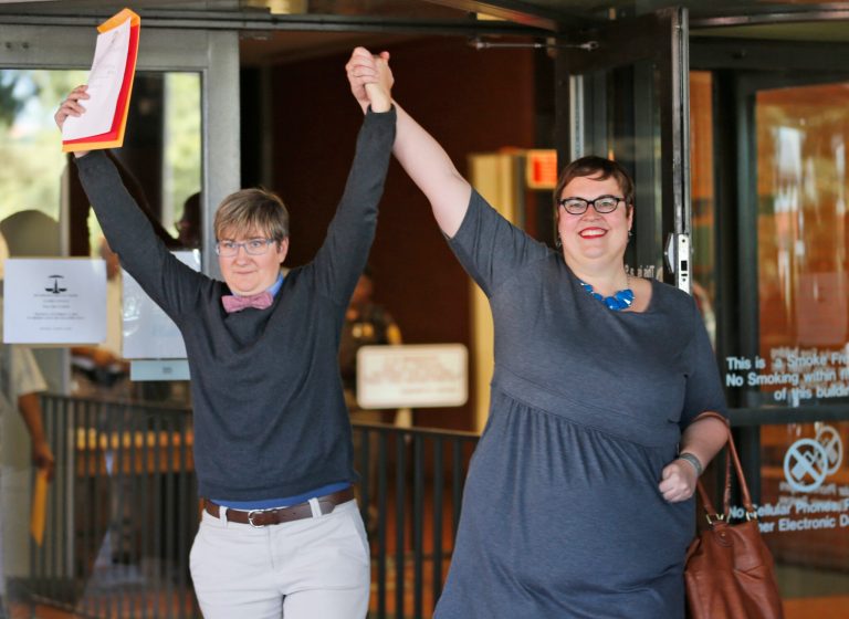 Nicole Pries, left, and Lindsey Oliver hold up their marriage license as they celebrate being one of the first same-sex couples in Virginia to be married outside a Richmond court building in Richmond, Va., Monday, Oct. 6, 2014. The Supreme Court's order turning way appeals from five states seeking to prohibit same-sex marriage has triggered a series of moves in affected states to clear the way for gay and lesbian unions. (AP Photo/Steve Helber)