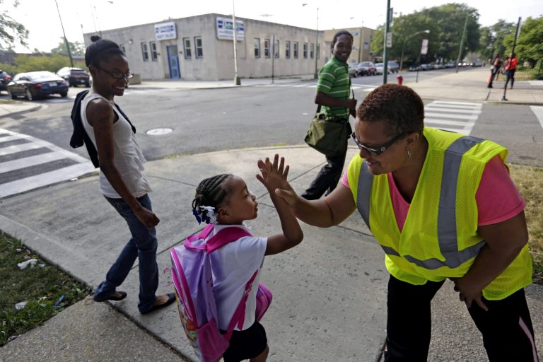   FILE - In this Aug. 26, 2013 file photo safety guard Renee Green high-fives Demari Hill, 5, as she heads to Gresham Elementary School with her parents Destiny and Anthony Hill on her first day of kindergarten classes in Chicago. The National Center for Education Statistics estimated that in 2013, 50.1 million children will be enrolled in U.S. public schools and 5.2 million will be in private school. That doesnât include home-schooled students, an estimated 1.5 million in 2007, which home-school advocates say are higher now. As for teachers there are about 3.3 million elementary and secondary public teachers in 2013, leading to a student teacher ratio of 15-to-1, NCES said. (AP Photos/M. Spencer Green, File)  