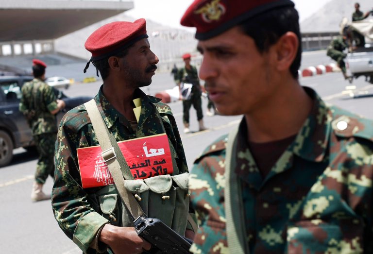 A Yemeni soldier, left, wears a placard with Arabic writing that reads,