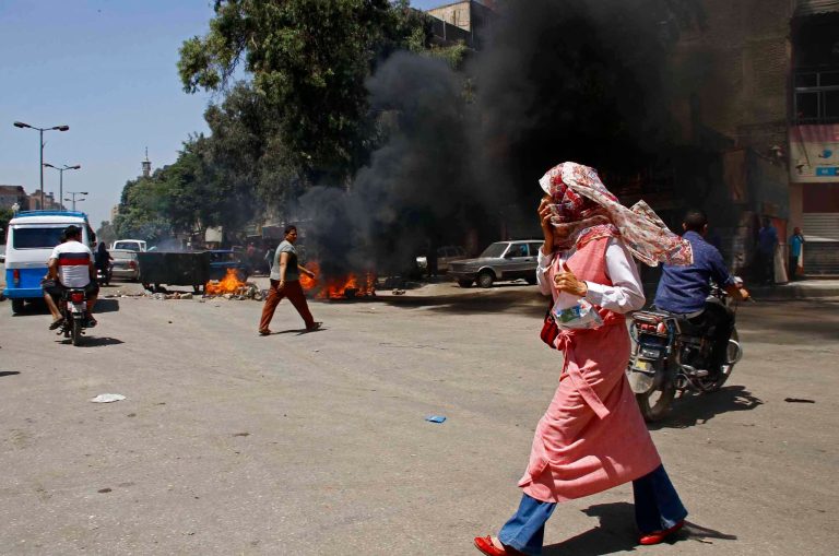 An Egyptian woman covers her mouth from heavy smoke after supporters of ousted President Mohammed Morsi blocked a road by setting waste on fire in Matariya Square, Cairo, Egypt, Thursday, Aug. 14, 2014. Egyptian security forces firing tear gas quashed small, scattered demonstrations on Thursday by Islamist supporters of ousted President Mohammed Morsi who tried to commemorate the anniversary of the killing of hundreds of protesters. (AP Photo/Ahmed Abdel Fattah, El Shorouk Newspaper) EGYPT OUT