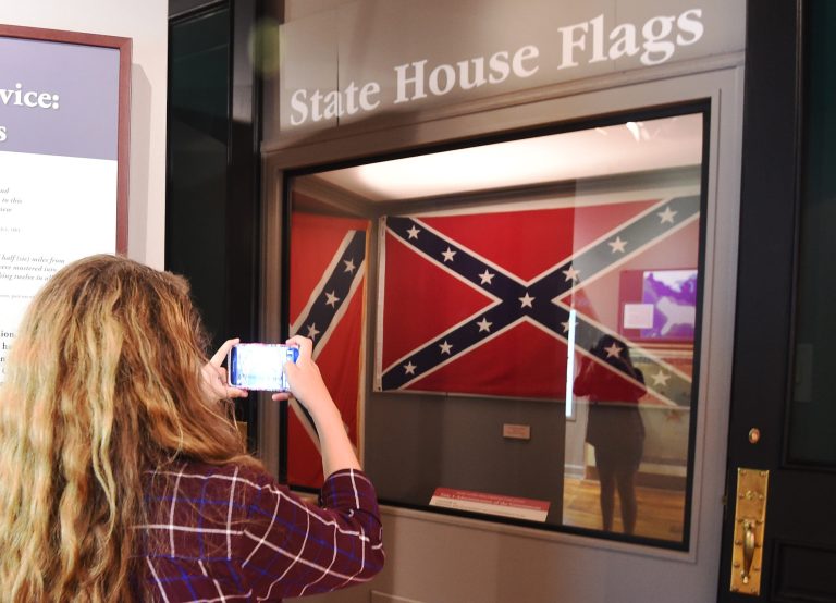Alyssa Daniels of Atlanta takes a photograph of the Confederate flags that once flew at the South Carolina Statehouse at the South Carolina State Museum, Wednesday, June 24, 2015, in Columbia, S.C. (AP Photo/Rainier Ehrhardt)