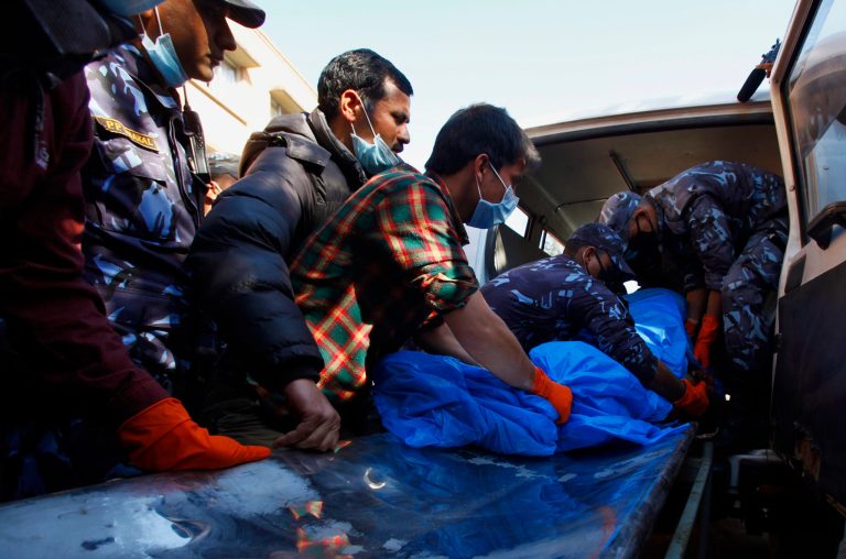Hospital officials and Nepalese police officers carry the remains of a plane crash victim out from an ambulance upon arrival at a teaching hospital in Katmandu, Nepal, Monday, Feb. 17, 2014. Rescuers on Monday found the wreckage of the passenger plane that slammed into a snow-covered mountain and burst into flames, killing all 18 people on board, including a small child, authorities said. (AP Photo/Niranjan Shrestha)