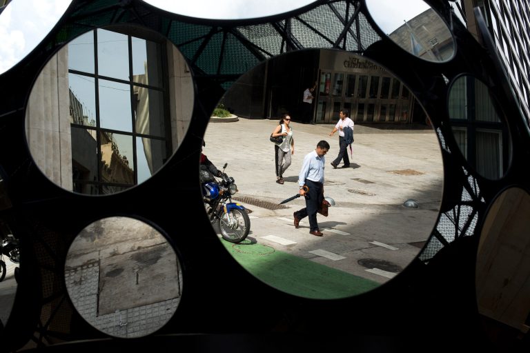 FILE - In this Tuesday, Jan. 28, 2014 file photo, office workers are reflected in a building's decorative mirrors in downtown Buenos Aires, Argentina. When Argentina fell into the economic abyss a decade ago after defaulting on its sovereign debt, Brazil suffered right along with it, nearly following its neighbor into insolvency. Now, with Argentina's economy again facing a currency plunge and inflation spike, its ability to inflict economic damage on Brazil has greatly diminished. (AP Photo/Victor R. Caivano, File)