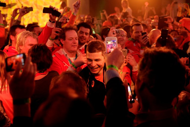 Under orange lighting, gold medallist Sven Kramer of the Netherlands walks through a crowd of cheering fans after winning the gold in the men's 5,000-meter speedskating race  at the 2014 Winter Olympics in Sochi, Russia, Saturday, Feb. 8, 2014. Kramer set a new Olympic record in the race. (AP Photo/Matt Dunham)
