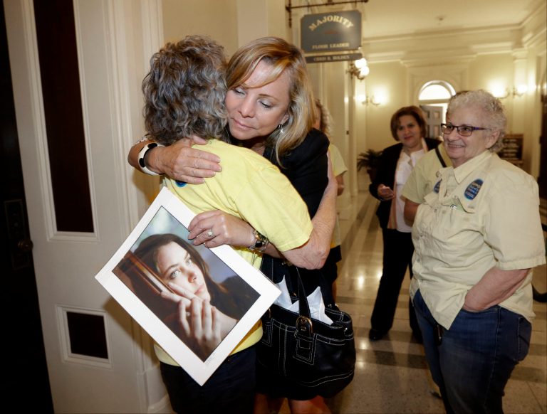 Debbie Ziegler holds a photo of her late daughter, Brittany Maynard, as she receives congratulations from Ellen Pontac, left, after a right-to die measure was approved by the state Assembly in Sacramento, Calif. (AP Photo/Rich Pedroncelli, file)