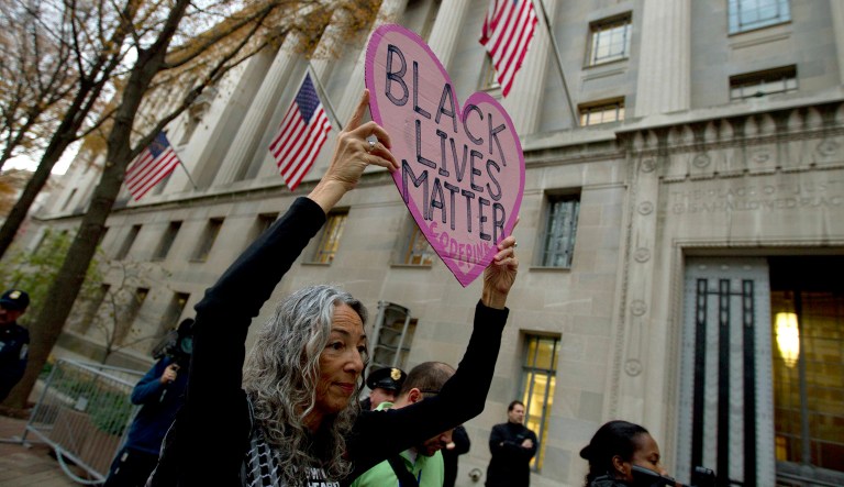 Desiree Fairooz holds up a sign during a protest. Fairooz was convicted for laughing at then-Attorney General nominee Jeff Sessions during his congressional hearing. (AP Photo/Jose Luis Magana)