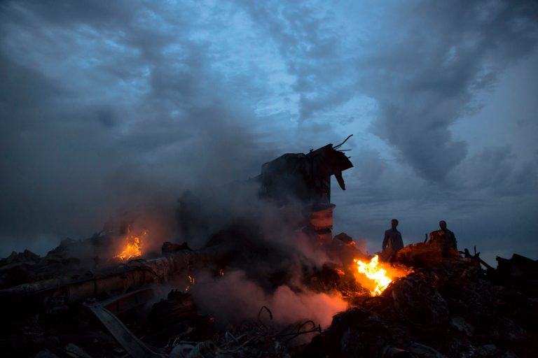 File - This July 17, 2014, file photo show people walking amongst the debris at the crash site of Malaysia Airlines Flight 17 near the village of Hrabove, eastern Ukraine.  Ukraine said the passenger plane was shot down as it flew over the country, killing all 298 people on board. Aviation has suffered one of its worst weeks in memory, a cluster of disasters spanning three continents. (AP Photo/Dmitry Lovetsky, File)