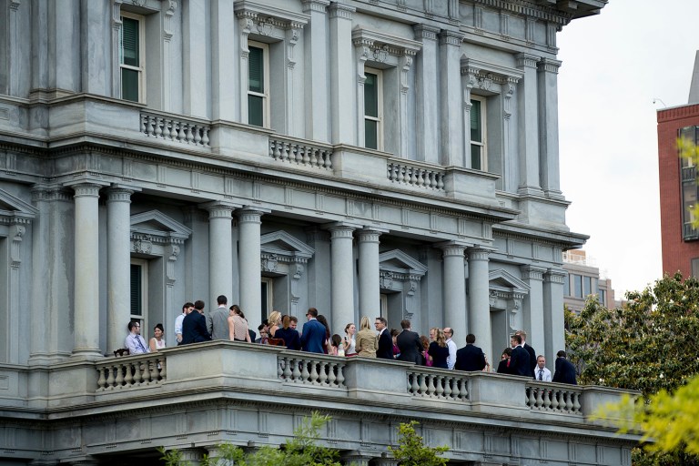 Staff members socialize and drink from red solo cups on a balcony in the Eisenhower Executive Office Building on the White House complex. (AP Photo/Andrew Harnik)