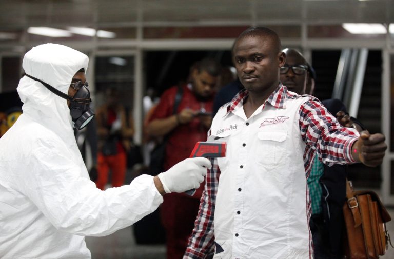FILE - In this Aug. 6, 2014 file photo, a Nigerian port health official uses a thermometer on a worker at the arrivals hall of Murtala Muhammed International Airport in Lagos, Nigeria. As the Ebola outbreak in West Africa grows, airlines around the globe are closely monitoring the situation but have yet to make any drastic changes. (AP Photo/Sunday Alamba, File)