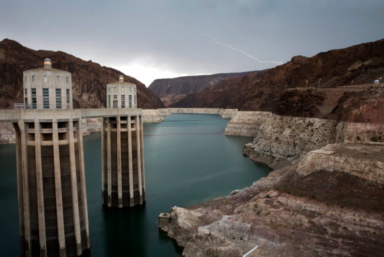 In this July 28, 2014 photo, lightning strikes over Lake Mead near Hoover Dam at the Lake Mead National Recreation Area in Arizona. On the left are the Arizona intake towers of Hoover Dam. The bathtub ring of light minerals shows the high water mark of the reservoir which has shrunk to its lowest point since it was first filled in the 1930s. (AP Photo/John Locher)