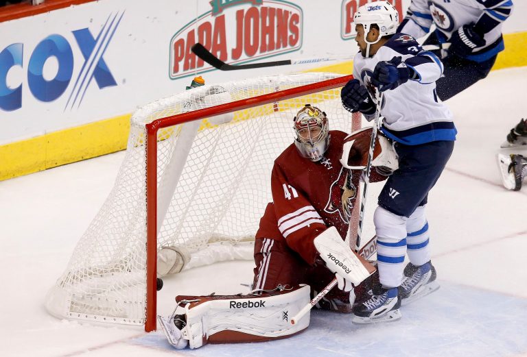 Winnipeg Jets' Dustin Byfuglien, right, scores against Arizona Coyotes' Mike Smith (41) during the second period of an NHL hockey game Thursday, Oct. 9, 2014, in Glendale, Ariz. (AP Photo/Ross D. Franklin)