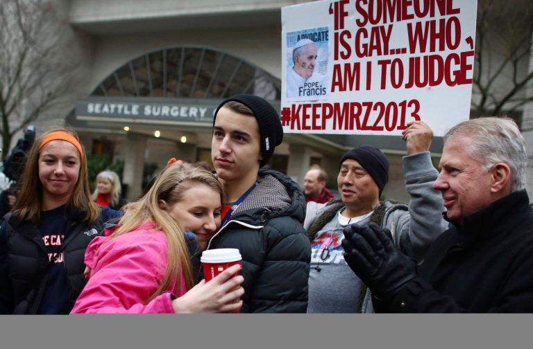 EastsideÃÂ CatholicÃÂ High School senior Julia Troy hugs student organizer and classmate Ian Edwards outside of the Chancery building for the Archdiocese of Seattle as Seattle Mayor-elect Ed Murray applauds, right, in Seattle on Friday. (AP/Joshua Trujillo)